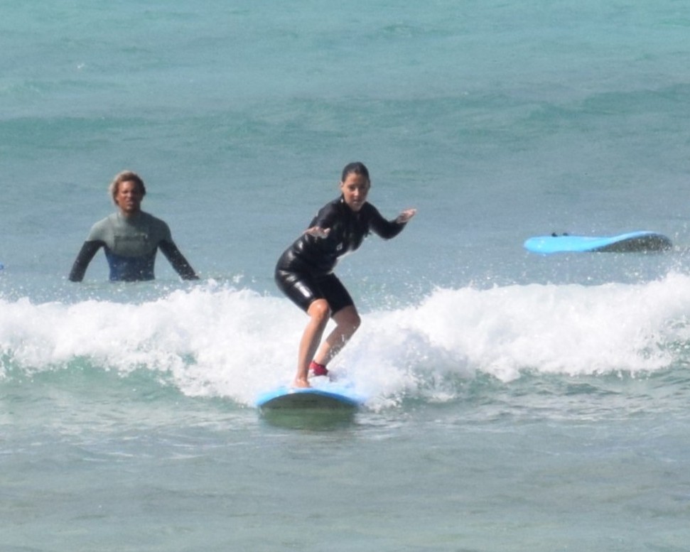 Beginner surfer riding a small wave with instructor support during a surf lesson in Boa Vista
